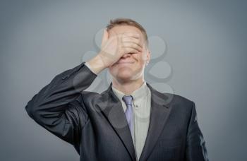 Portrait Of An Businessman Covering Eyes Isolated On Grey Background