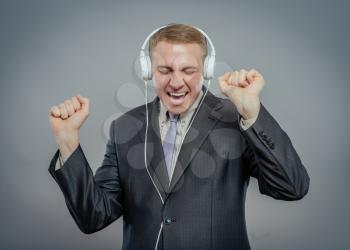 Studio shot of   businessman with headphones, listening to music and dancing