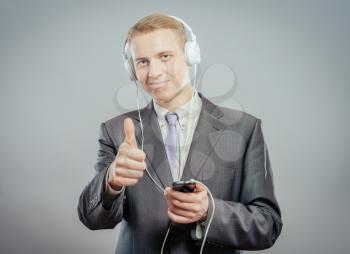 Studio shot of modern  businessman with headphones, listening to music and dancing