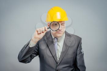 engineer man in helmet with a magnifying glass, focus on the glass