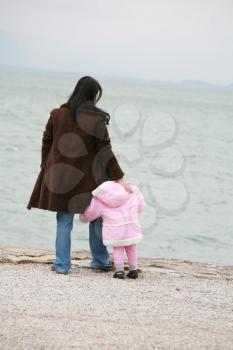 Mother and daughter looking the sea on winter