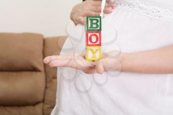pregnant woman having the word boy with wooden blocks written on her hand