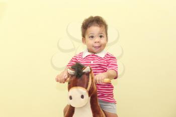 Portrait of an adorable african boy in his horse toy.