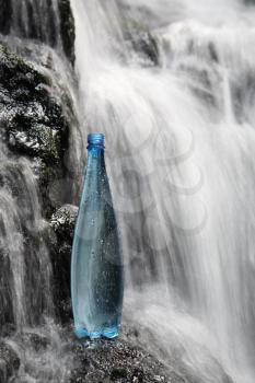 A blue bottle of fresh mineral water in waterfalls