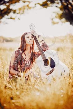 Portrait of a lovely young hippie girl with guitar. Outdoor shot
