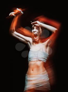 Horror shot: strange crazy young woman drives a nail into her head. Blurry photo