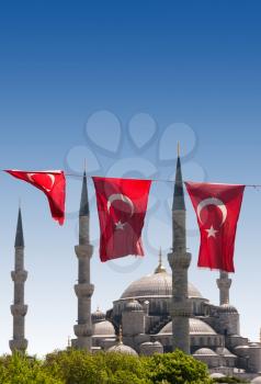 Mosque behind turkish flags in blue sky
