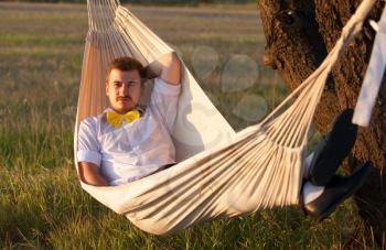 Young man swinging in hammock at sunset
