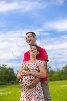 Husband hugs his pregnant wife oudoor
