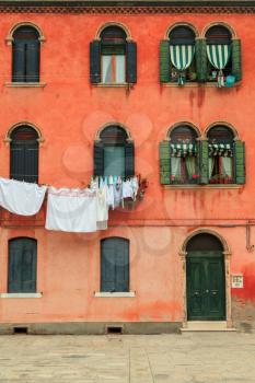 Facade of the red vintage house with drying clothes in Venice
