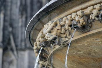 Ugly demon statue with streaming water from mouth near Cologne cathedral, Germany

