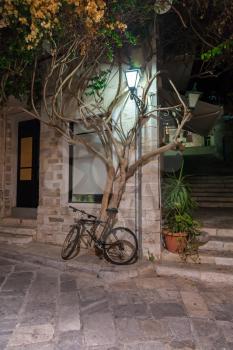 Bicycle near tree on the city street on Greece island
