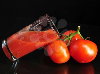 fresh tomatoes and tomato juice on black background