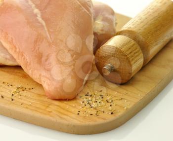 Raw chicken breast meat on wooden chopping board