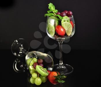 assortment of fresh fruits in a wineglass on black background