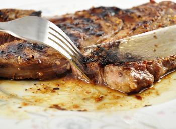 a fresh grilled steak on a plate  ,close up, with fork and knife