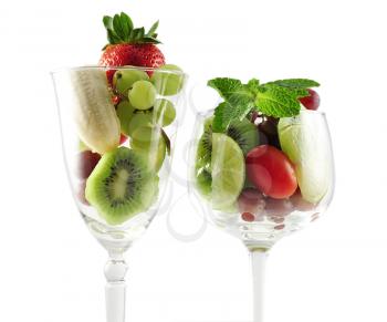 assortment of fresh fruits in a wineglass on white background