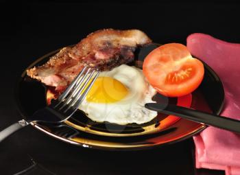 egg and bacon on black background