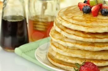 stack of pancakes with maple syrup,honey and berries