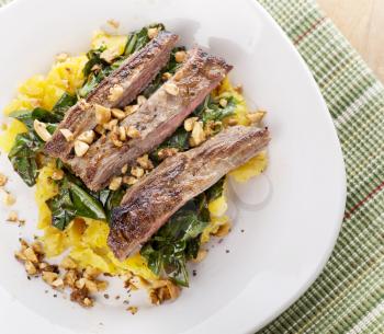 flank steak with mashed plantain , collard greens and ginger peanuts 