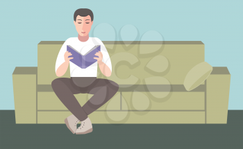 A man sits on a sofa and reading a book