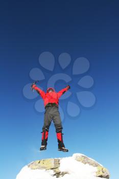 Royalty Free Photo of a Mountain Climber Jumping on a Peak