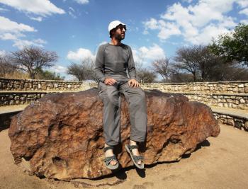 Royalty Free Photo of a Tourist Sitting on the Hoba Meteorite in Namibia