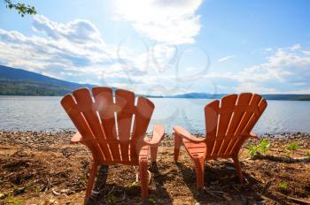Red comfortable deck chairs on the lake in Canada. Canadian travel concept