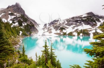 Serene scene by the mountain lake with reflection of the rocks in the calm water.