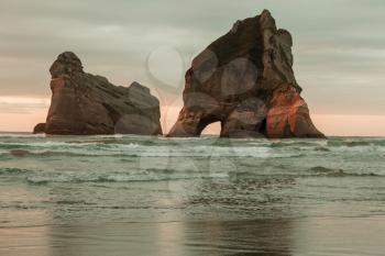 The Archway Islands of Wharariki Beach at sunset in New Zealand