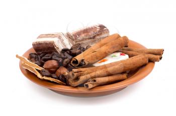 Sweets, cinnamon, nuts and coffee beans on a saucer isolated on white