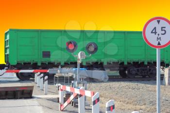 railroad cars at the crossing with a barrier and a red traffic light.