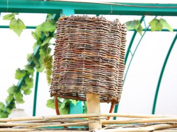 The wattled basket hangs on a wattled fence upside down