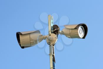 Two security cameras against blue sky