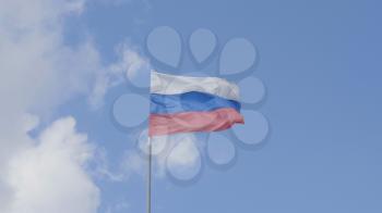 Russian flag on the flagpole waving in the wind against a blue sky with clouds.