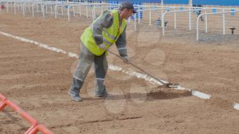 The worker rakes the sand with rakes. UltraHD stock footage.