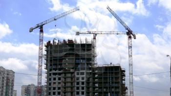 Tower cranes against blue sky, with clouds. Timelapse. UltraHD stock footage.