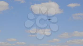 Helicopter of green color flies against a background of white clouds.