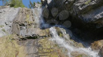 Big beautiful waterfall flows down the rocks mountains.
