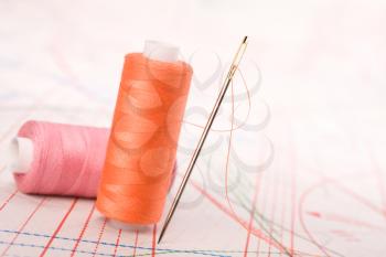 Spool of thread and needle. Sew accessories on blurred background.