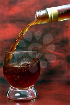 alcohol drink pouring into glass on red background