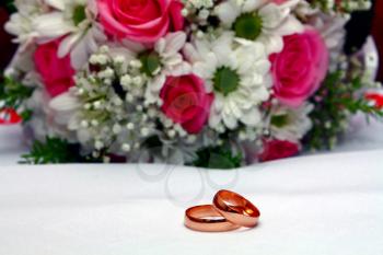 two wedding rings and bouquet isolated on white background