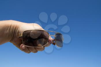 Glasses in hand man on a background of blue sky