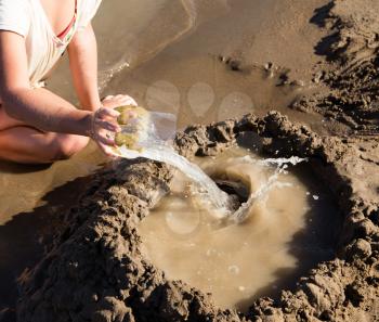 Girl playing in the sand on the lake .