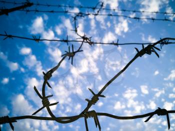 Barbed wire against the sky with clouds .