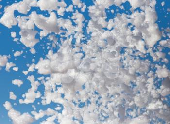 White foam against the blue sky as background .