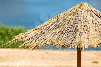 Straw umbrella from the sun on the lake to the beach