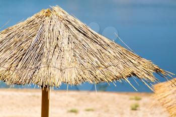 Straw umbrella from the sun on the lake to the beach
