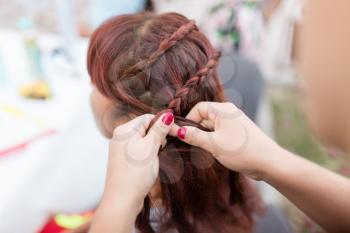 the stylist weaves the female braids on the head .