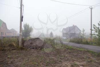 the road in the village in the fog in the morning .